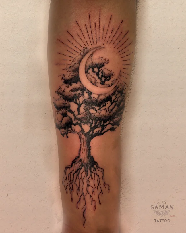Tatouage d’un arbre aux racines apparentes, sous un croissant de lune entouré de rayons.