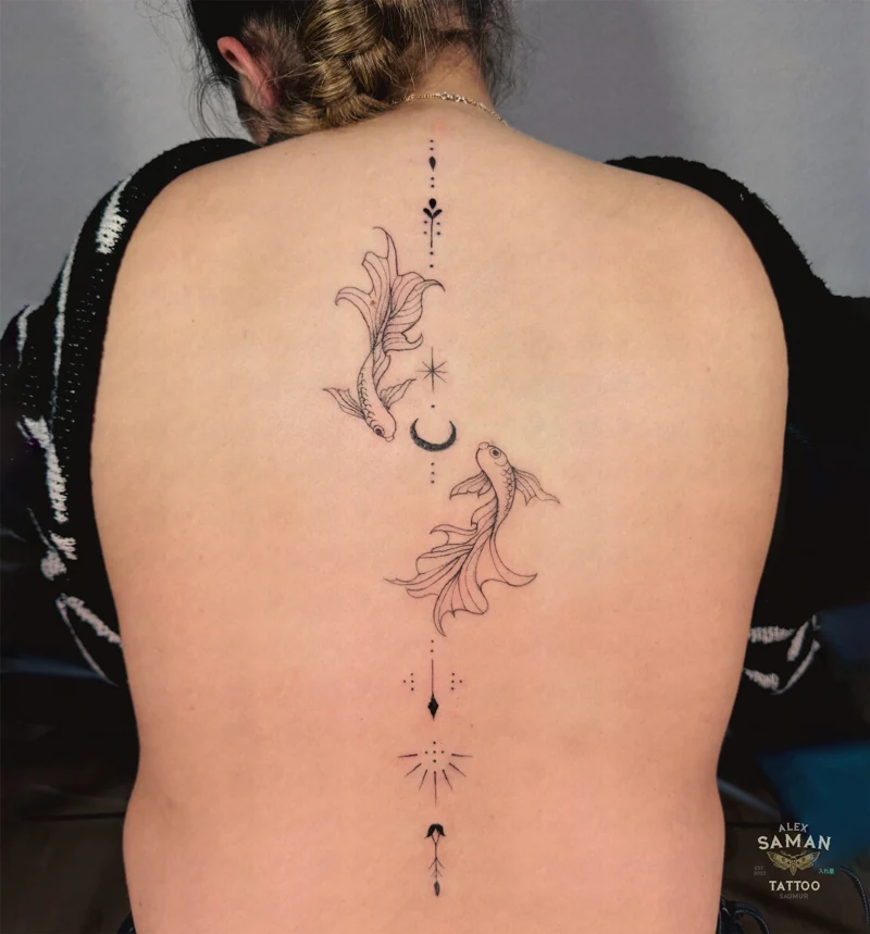 Tatouage de deux carpes accompagnées de lunes et d’ornements fins le long du dos.