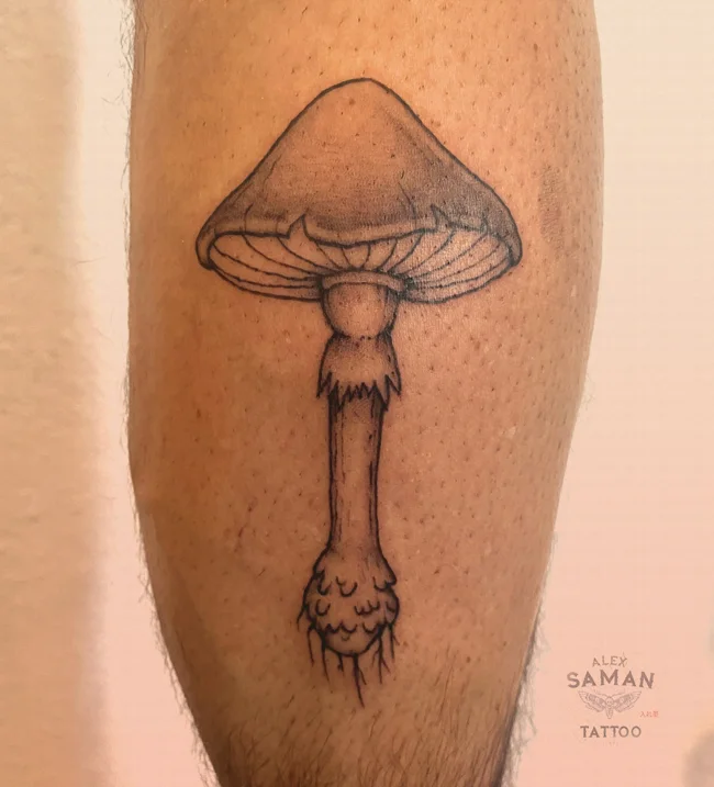 Tatouage d’un champignon à large chapeau, avec des lamelles et des ombrages délicats.