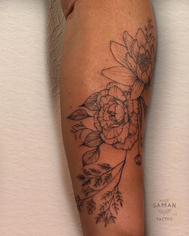 Composition de lotus, de boutons et de feuillages tatouée sur le bras.