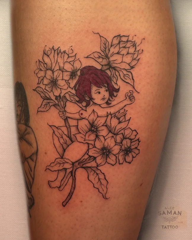 Tatouage d’un personnage féminin aux cheveux rouges, entouré de fleurs dessinées en lignes fines.