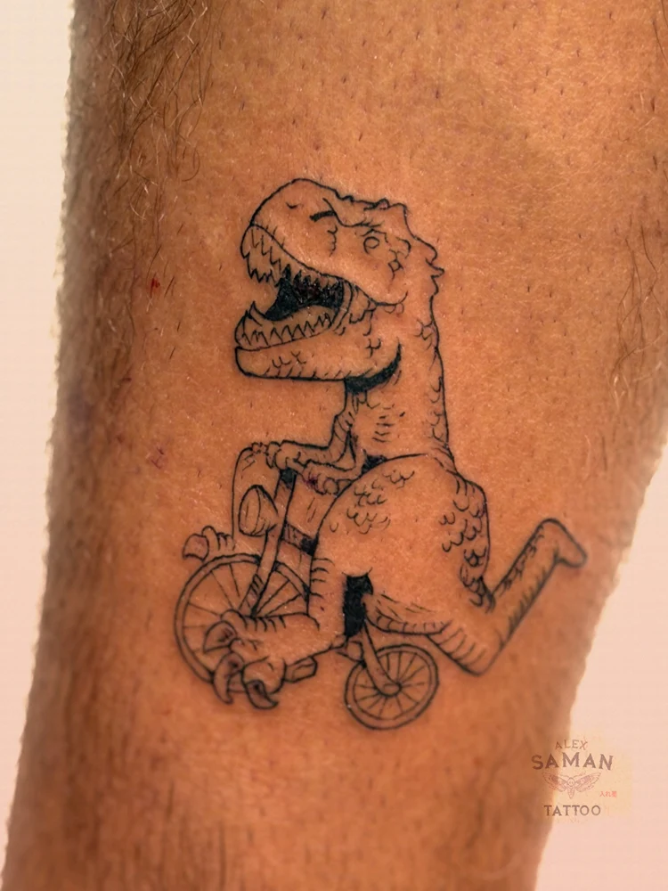 Tatouage d’un tyrannosaure sur un petit vélo, dessiné au trait noir.